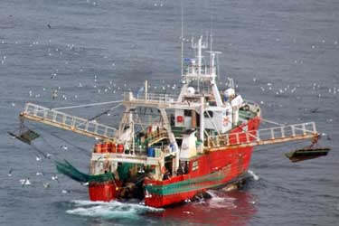A photograph of a Argentine langostino fishing vessel with its booms out getting ready to launch its nets.